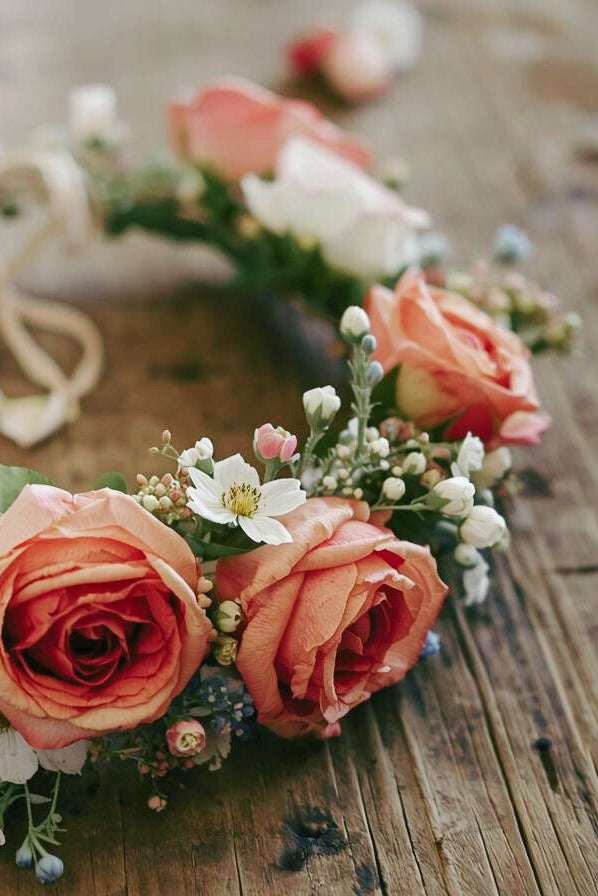 Floral headband with pink and orange roses on a wooden surface
